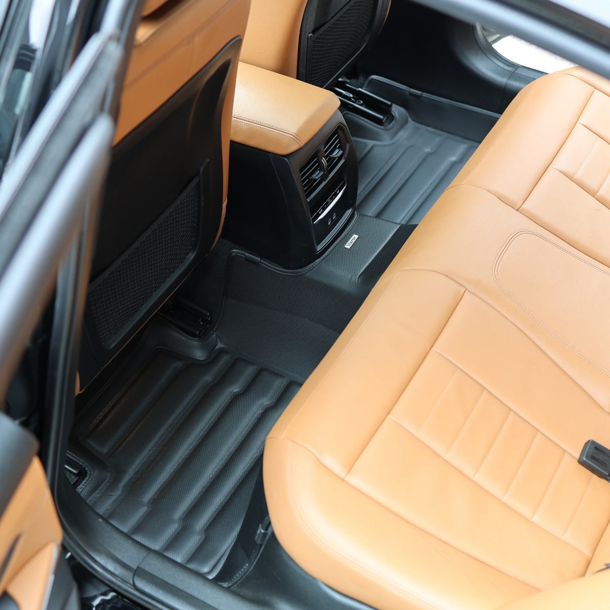 Rear row with tan leather seats and a black mat covering the whole rear floor
